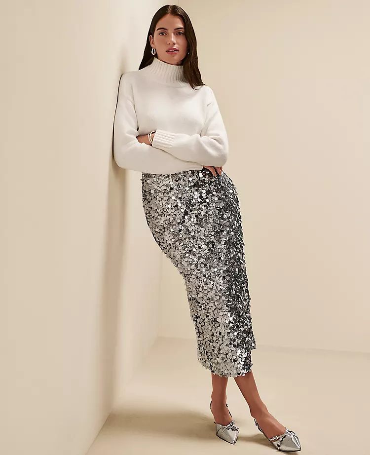 A woman is wearing a white turtleneck knitted sweater paired with sequins skirt