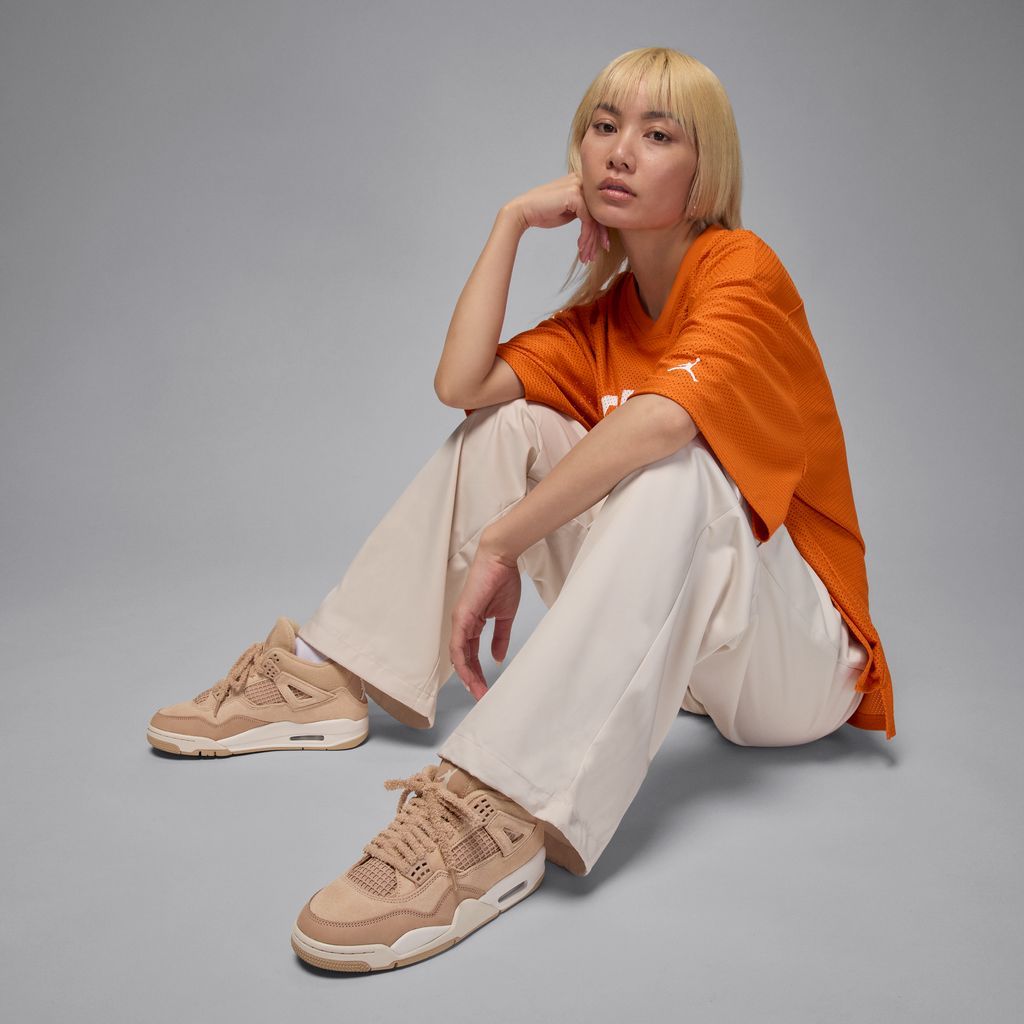 Model in orange oversized T shirt and white jeans 