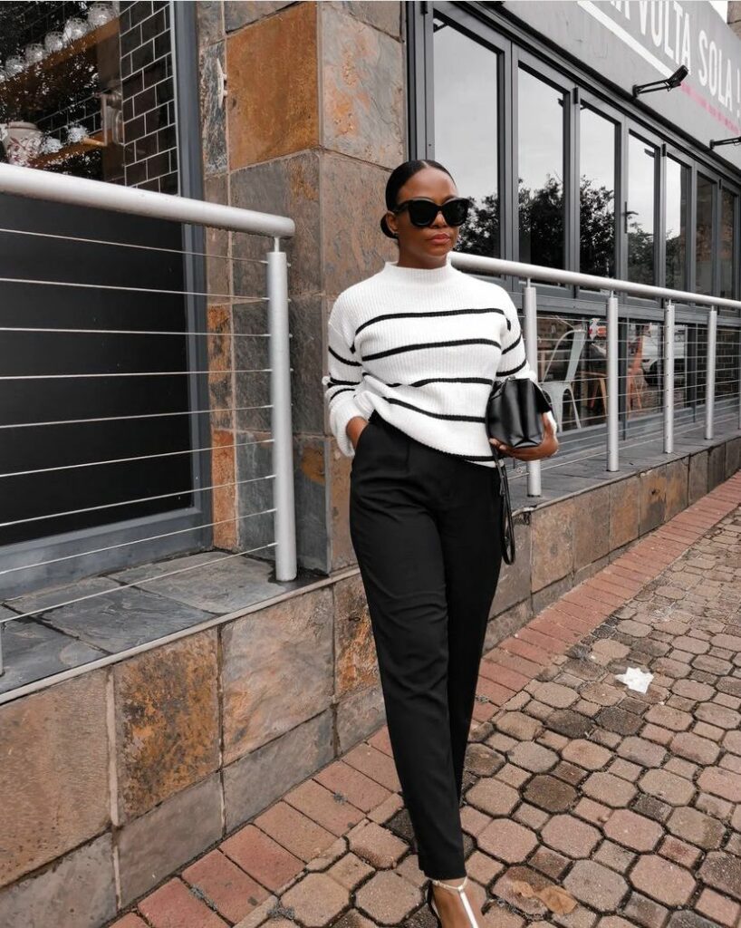 Model in white sweater with black horizontal lines with black slacks 
