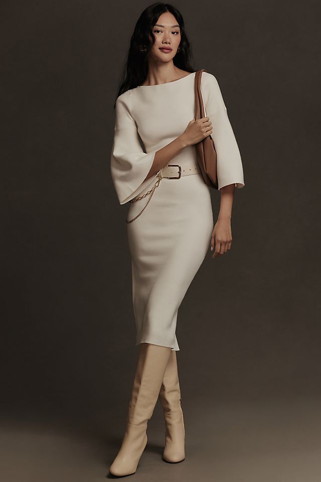 Model in conservative white dress with white belt and calf high boots 