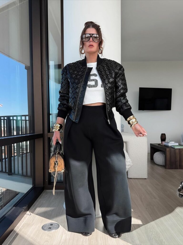 Model in black oversized slacks, white crop top and braided leather jacket elevated minimalism