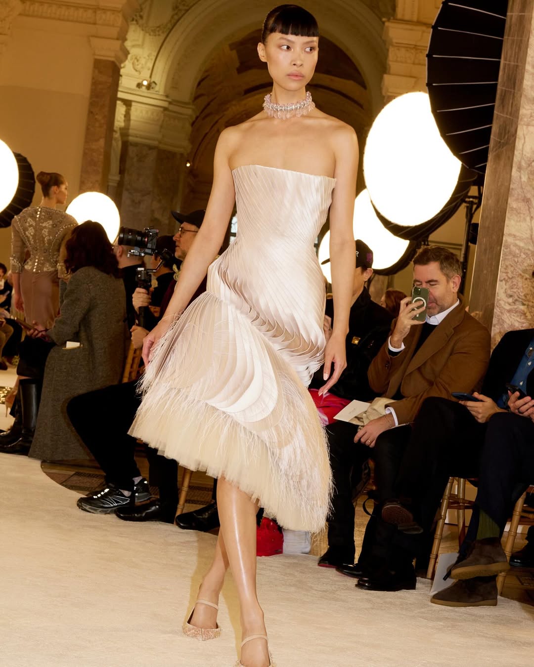 The Schiaparelli Haute Couture Spring/Summer 2025 collection included a bustier dress made of pearl grey duchess satin ribbons twisted around the body and finished in tonal petals embroidered with a cloud of ostrich feathers bathed in glycerin