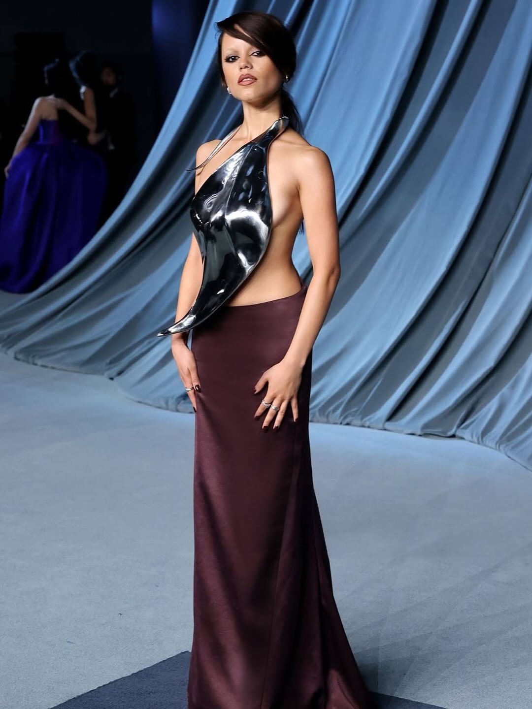 Jenna Ortega wore a Grace Ling Spring 2026 dark silver metallic breastplate that mimicked a leaf. Matched with a burgundy silk skirt.