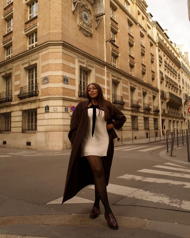 white mini dress with black trim and long burgundy coat 