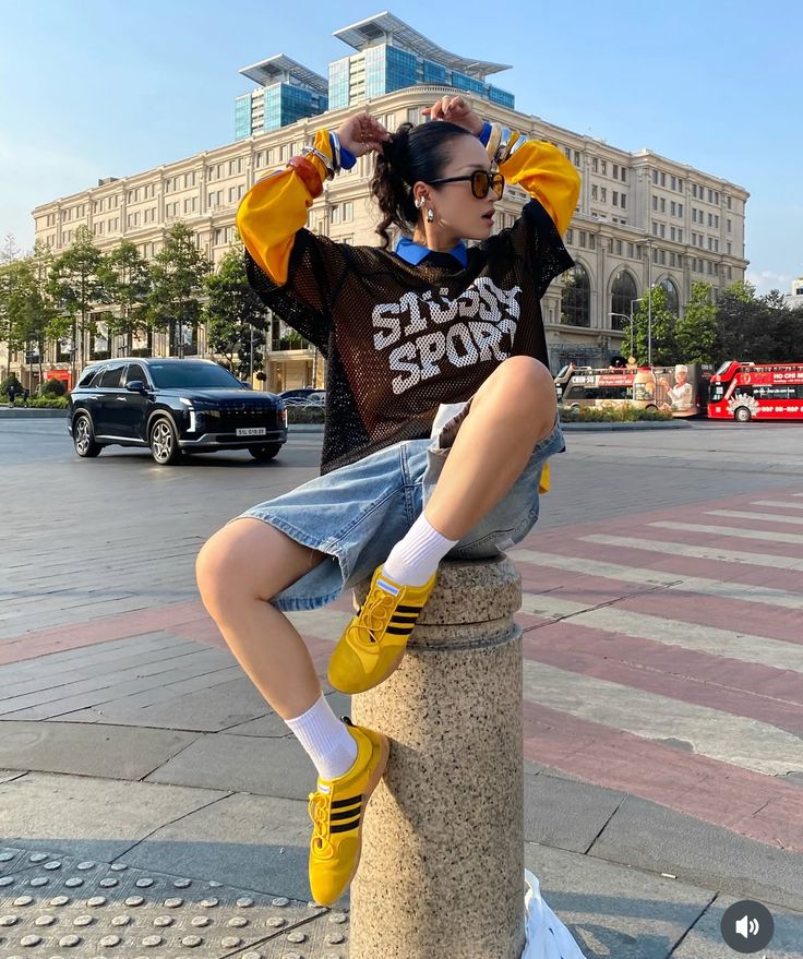 model in mesh T shirt over yellow long sleeve t shirt with oversized denim shorts 