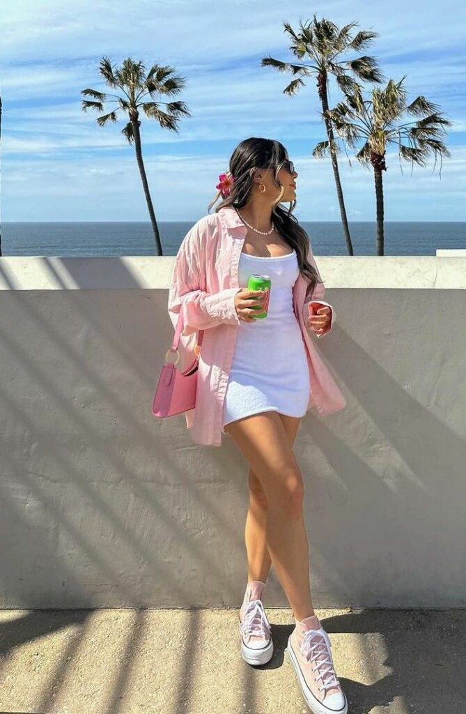 Model in pink oversized dress shirt and white mini dress