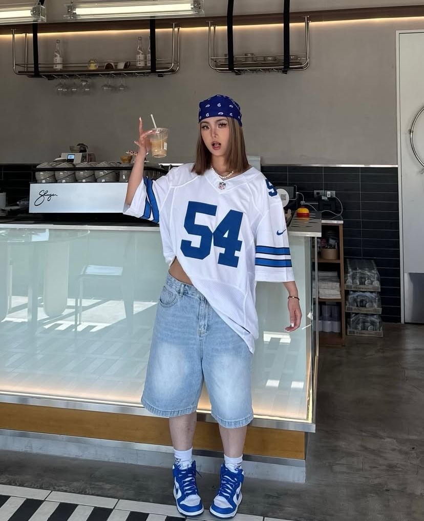 statement streetwear girl in Cowboys jersey and oversized shorts
