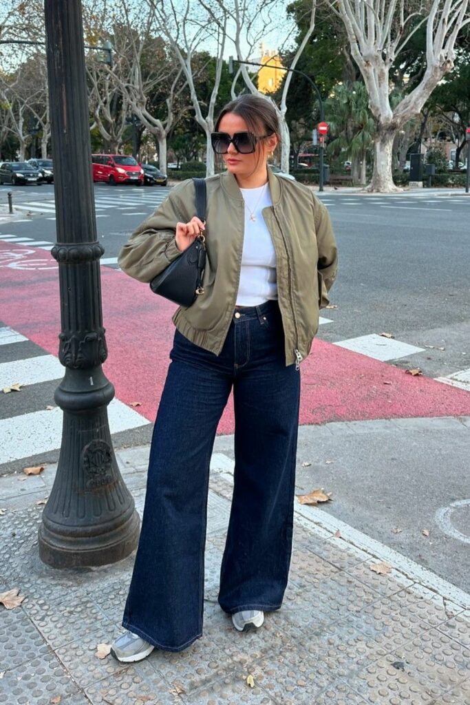 comfortable white crop top with denim bell bottom jeans and gold bomber jacket