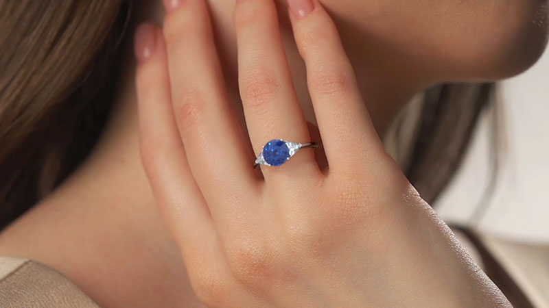 a woman is wearing a blue sapphire ring