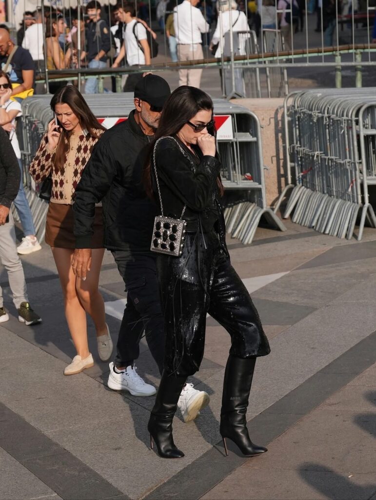 Anne Hathaway in black top with black capri pants and knee high boots