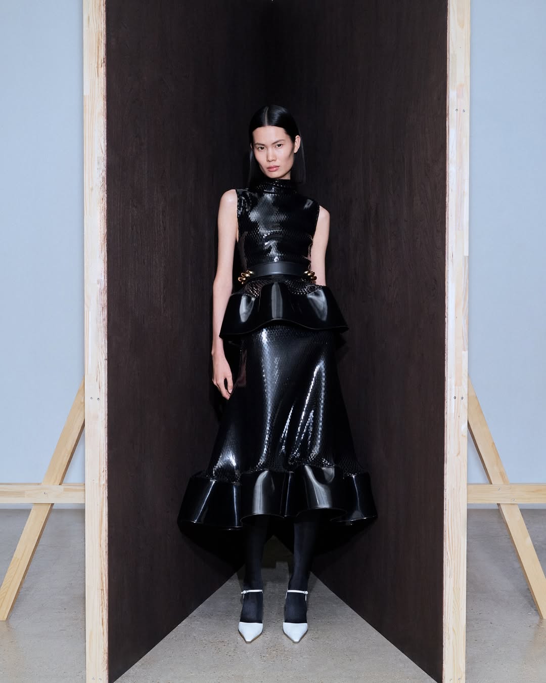 Alaïa’s Winter/Spring 2026 “Archetypes” collection featured a monochrome design with a patent leather two-piece sleeveless peplum top and ruffled midi skirt.