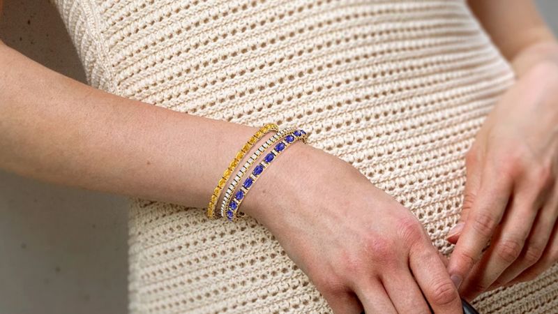 a woman layering a diamond bracelet with color gemstone bracelets
