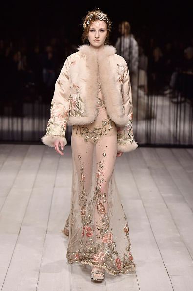 A model is wearing a custom-made powder pink satin shawl collar bomber and a slashed tulle dress with satin thread and sequin embroidery inspired by Alexander McQueen’s Fall/Winter 2016 collection.