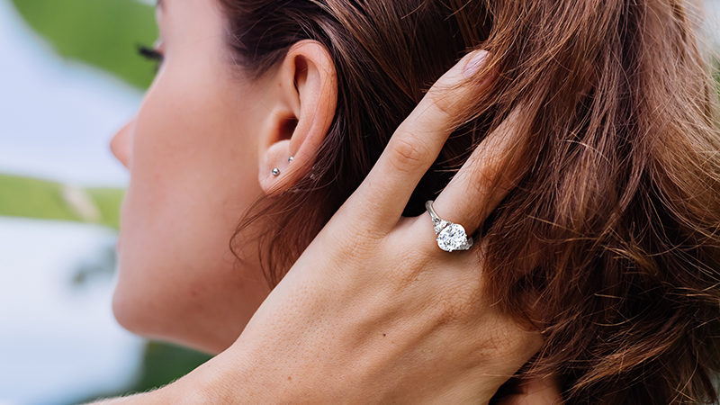 woman with a wedding ring on finger running fingers through her hair
