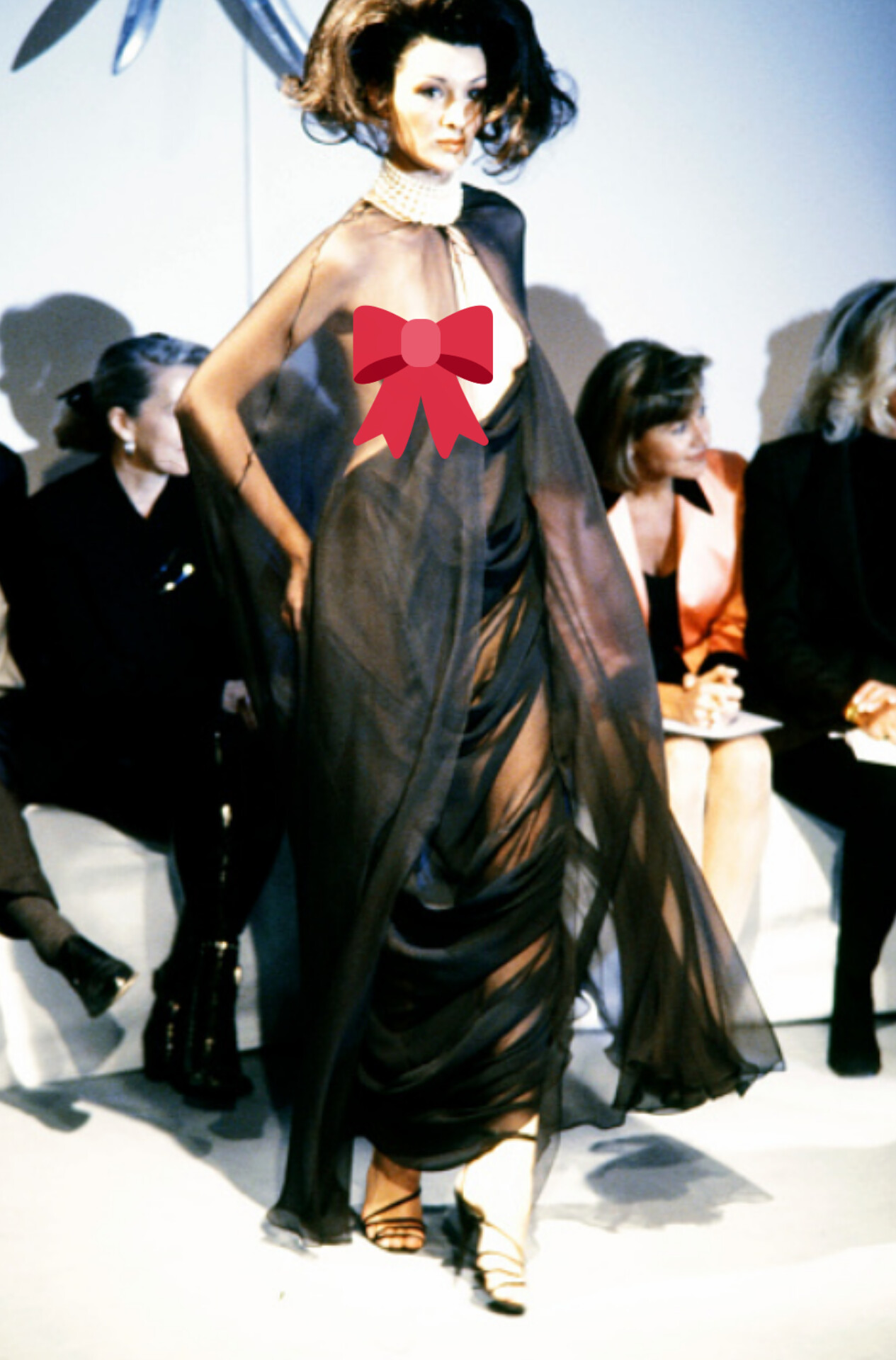 Erica Van Briel walks the runway for Thierry Mugler Haute Couture’s Spring/Summer 1998 collection, dressed in a translucent cloak and matching nipple ring set.