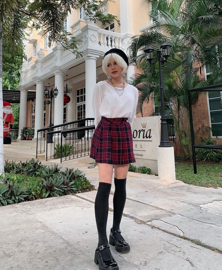 Model in white blouse with plaid pleated mini skirt and knee socks