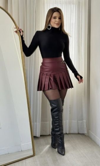 model in black form fitting long sleeve top and burgundy faux leather mini skirt