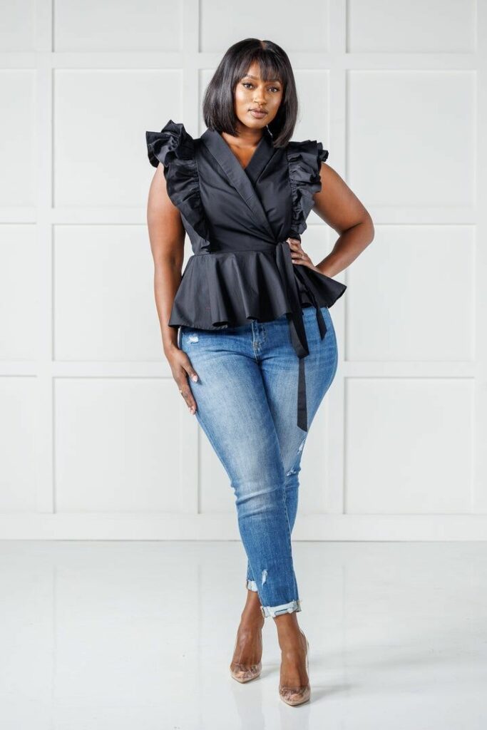 Plus sized model in black frilly sleeveless Peplos tops for plus size and blue jeans 