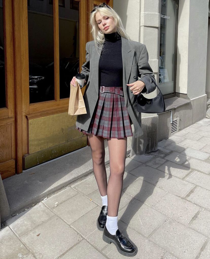 Model in gray blazer and plaid pleated mini skirt 