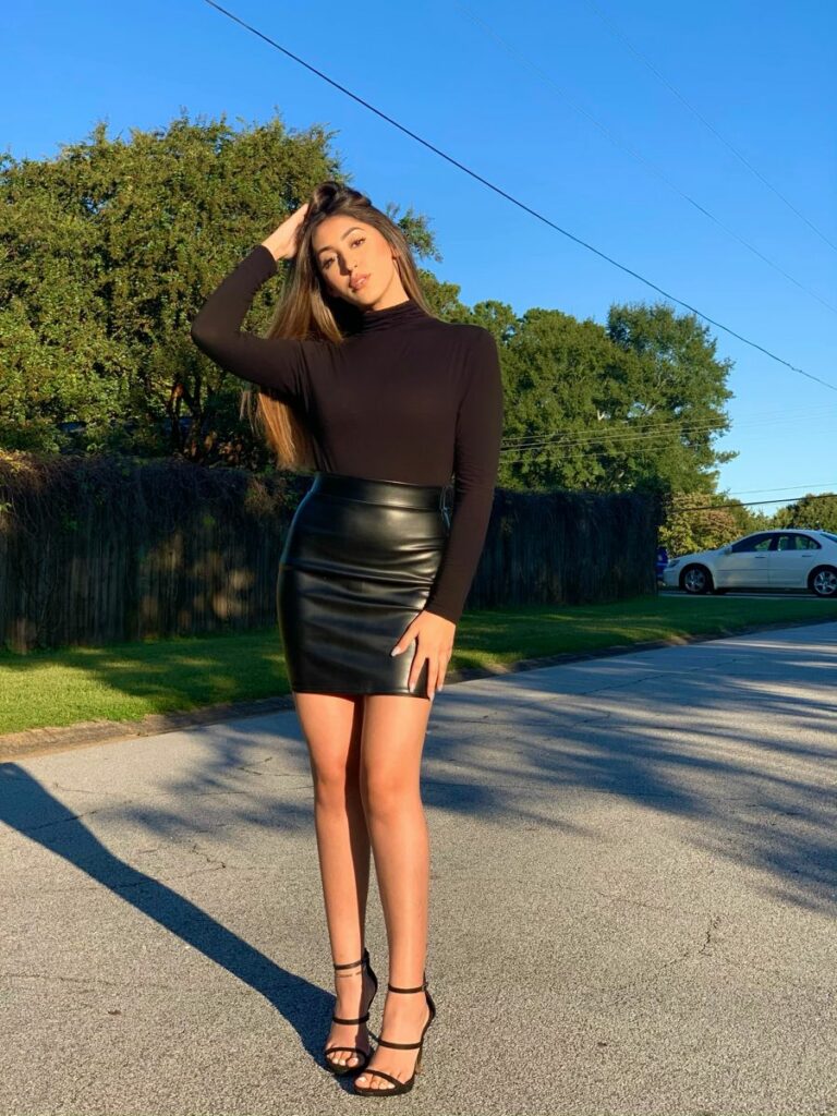 Model in long sleeve form fitting top and black leather mini skirt 
