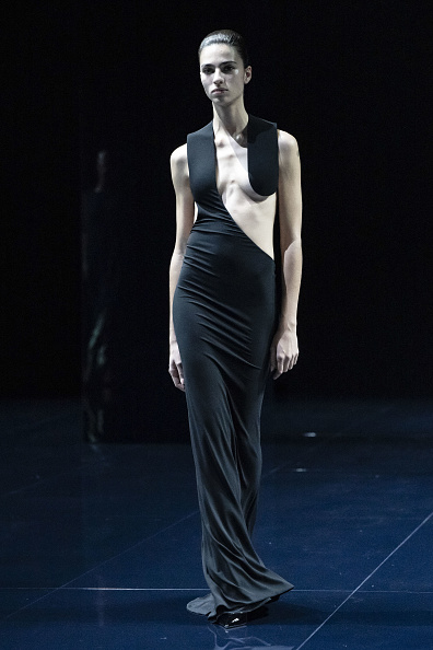 A fashion model walks down the runway for Tom Ford’s Spring/Summer 2026 collection, wearing a black asymmetrical deep-cut gown designed specifically for Teyana Taylor’s performance at the 68th Grammy Awards.