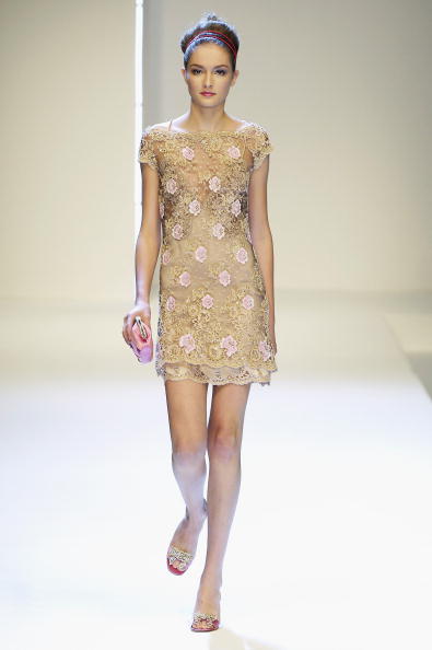 A fashion model walks along the runway wearing a short-sleeved, floral lace-embroidered minidress presented in the Valentino Women’s Spring/Summer 2007 collection.