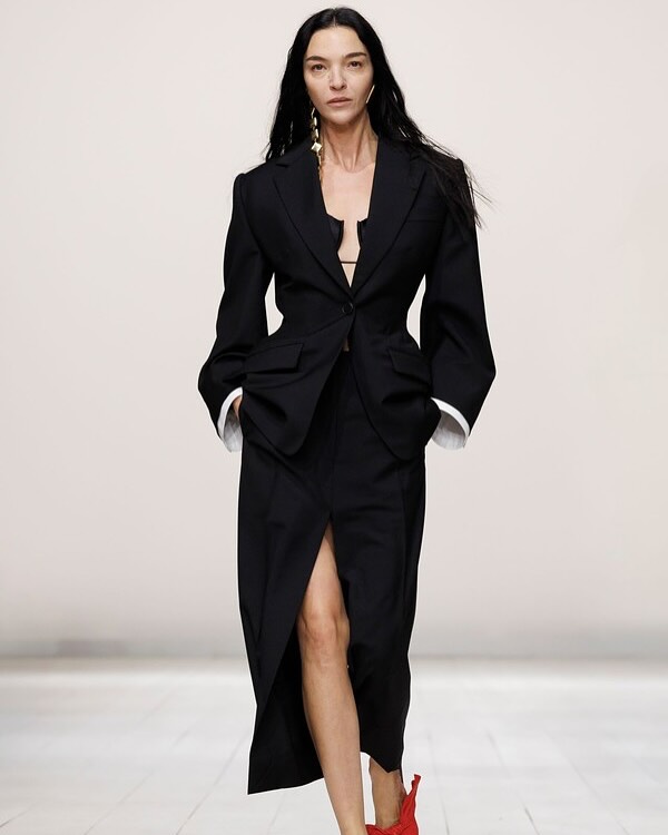 Mariacarla Boscono is seen striding along the runway at the Givenchy Womenswear Spring/Summer 2026 show, adorned in a draped grain de poudre wool jacket and a matching draped grain de poudre wool skirt ensemble.