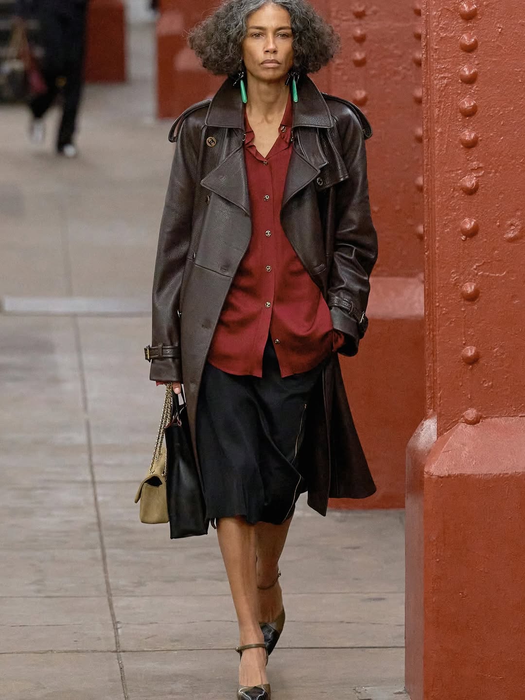 The model showcases a stylish black leather coat on the Chanel Métiers d’Art 2026 runway as she walks the catwalk.