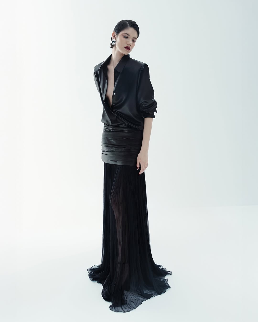 During the Cong Tri Fall/Winter 2025 ready-to-wear runway collection show, a model elegantly strutted in a two-piece ensemble consisting of a lacquer silk shirt paired with a chiffon-trimmed lacquer silk skirt.