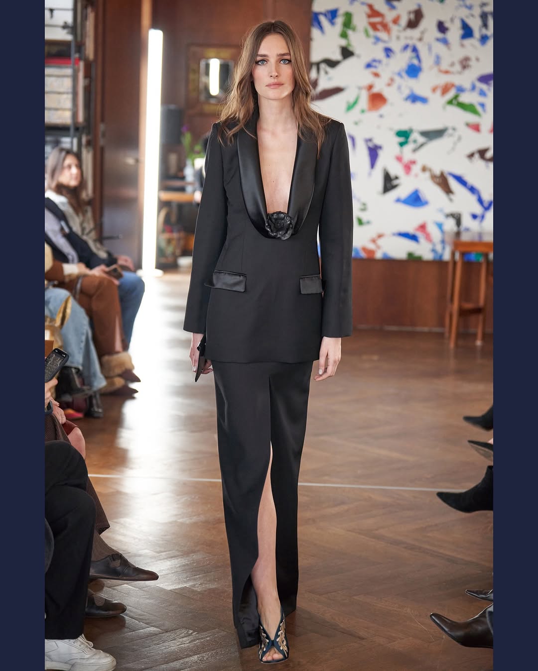 During the Julie de Libran Haute Couture Week Spring/Summer 2026 ready-to-wear runway collection show, a model presented an ensemble comprising a black V-neck tuxedo blazer adorned with floral appliqué, paired with a thigh-high split skirt suit.