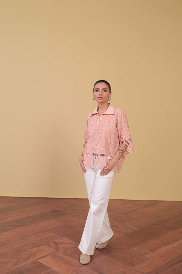 Model in pink blouse with lace overlay and white slacks