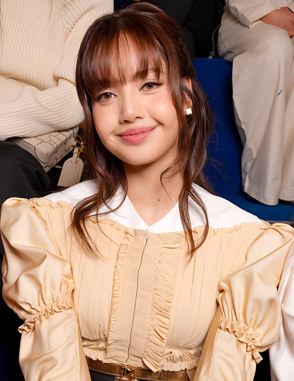 Blackpink Lisa was photographed sitting in the front row of the Louis Vuitton Fall/Winter 2026-2027 show, dressed in a beige satin crop top with an off-the-shoulder neckline that revealed a shirt underneath and accessorized with LV Cube earrings inspired by Pateki, a puzzle game invented by Gaston Vuitton in 1932.