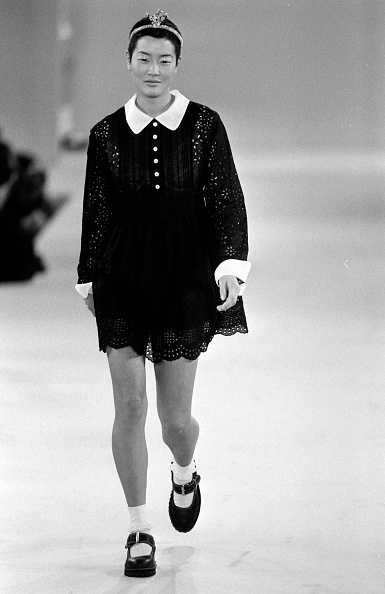 Model and actress Jenny Shimizu was seen walking the runway for Anna Sui’s Spring/Summer 1994 collection, displaying a black-and-white babydoll lace mini dress complemented by white knee-high socks and black patent leather platform sandals.
