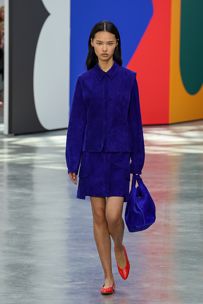 Haizhu Gu walked the runway for Akris Womenswear Spring/Summer 2026 in a cobalt blue suede two-piece jacket and skirt, accessorized with a matching large handbag and slingback shoes.