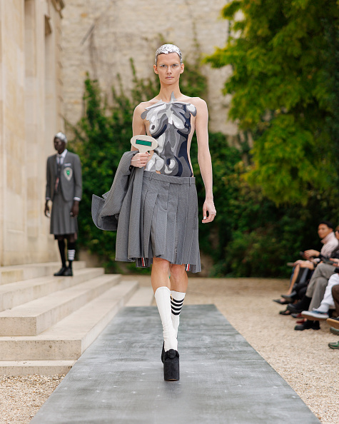 Daniela Kocianova strides down the runway at the Thom Browne Womenswear Spring/Summer 2026 show, showcasing a strapless multicolored top paired with a pleated midi skirt.