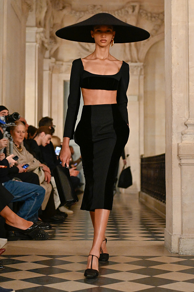 gettyimages-2257673392-594x594 | Fashonation A fashion model was spotted strolling down the catwalk of the Jacquemus Men’s Fall/Winter 2026 “Le Palmier” ready-to-wear collection at the Musée National Picasso-Paris, wearing a black two-piece long-sleeved crop top and high-waisted midi skirt combo, teamed with a matching wide-brimmed hat.