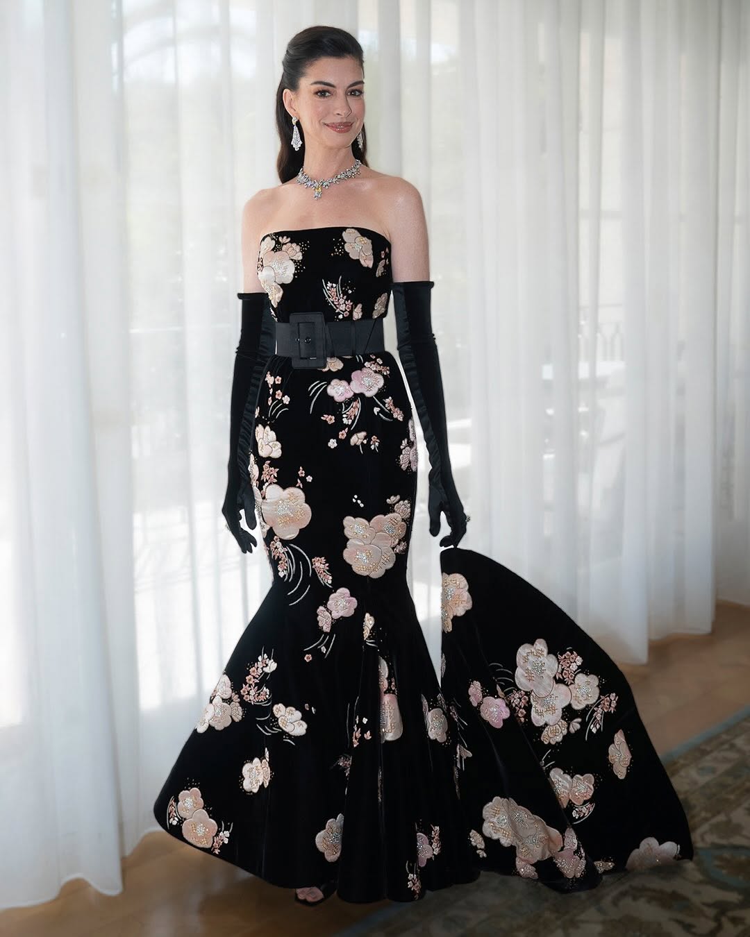 Anne Hathaway wore a Valentino couture off-the-shoulder floral-embroidered velvet mermaid gown to the 98th Academy Awards, complete with black velvet opera gloves, Roger Vivier Marlène strass sandals, and Bvlgari Eclettica high jewelry.