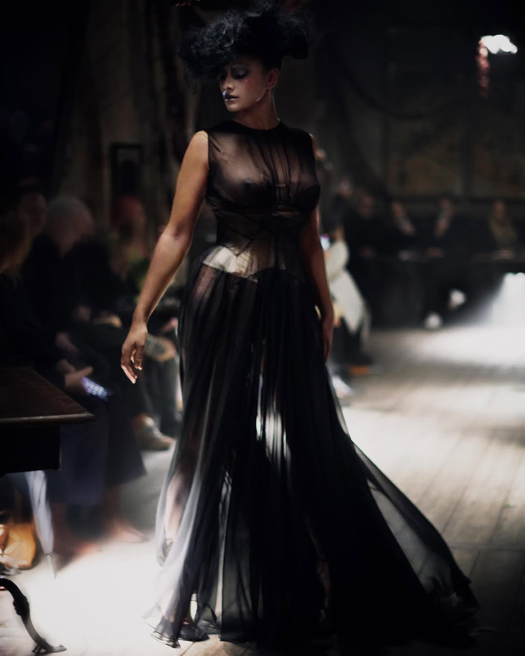 Jill Kortleve walked the Maison Margiela Artisanal collection 2024 runway in a black silk muslin dress, a boudoir-colored silk satin waist cincher, and black Tabi neoprene interwoven ankle-strap heels designed by Christian Louboutin for Maison Margiela.