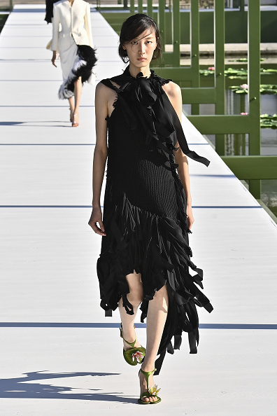 Xiru Yang walked the Christian Dior Fall/Winter 2026-2027 runway wearing a sleeveless, ripped asymmetrical midi dress with fringe, similar to what BLACKPINK Jisoo wore during the 2026 Canneseries International Festival.