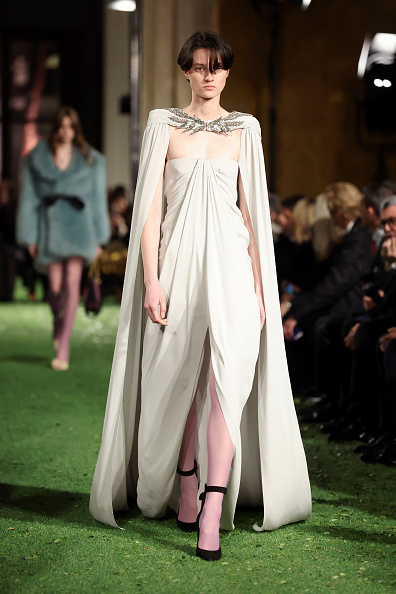 Tanya Churbanova graced the runway for Valentino’s Fall/Winter 2026 “Interferenze” collection, adorned in an off-white maxi cape featuring intricate embellishments, paired with a ruched gown in a coordinating hue beneath.