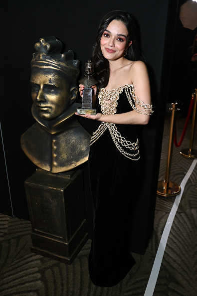 Rachel Zegler appeared backstage at the 2026 Olivier Awards, taking home Best Actress in a Musical for “Evita,” donning a Tamara Ralph haute couture black strapless velvet gown adorned with flowing gold crystal chains and Jimmy Choo Love pumps.