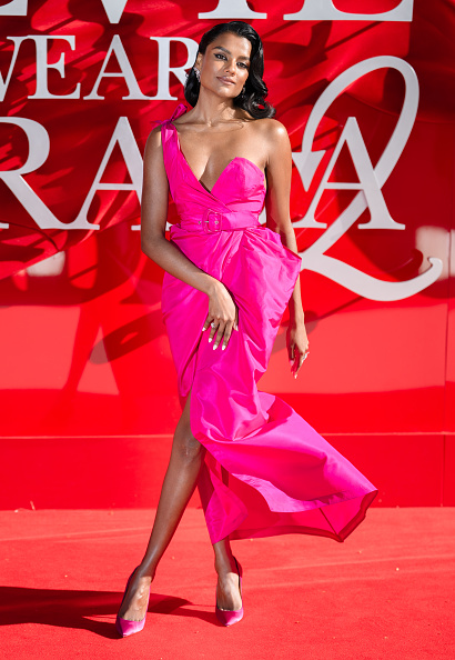 Simone Ashley is wearing a sleeveless hot pink satin bustier maxi dress inspired by the Thierry Mugler Resort 1984 ready-to-wear collection.