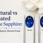 Two blue sapphires on forks labeled Natural and Heated, beside the headline 'Natural vs Heated Blue Sapphire: What Buyers Should Know'.