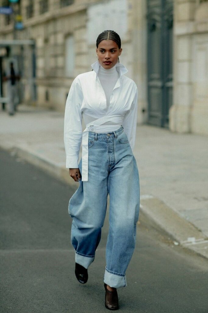 Model in white blouse and puffy faded jeans 