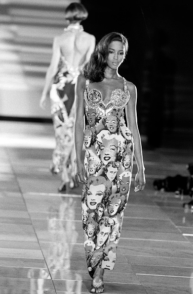 Naomi Campbell walked down the runway at Gianni Versace’s Spring/Summer 1991 collection show, wearing a sleeveless sheath maxi dress with patterns of James Dean and Marilyn Monroe.