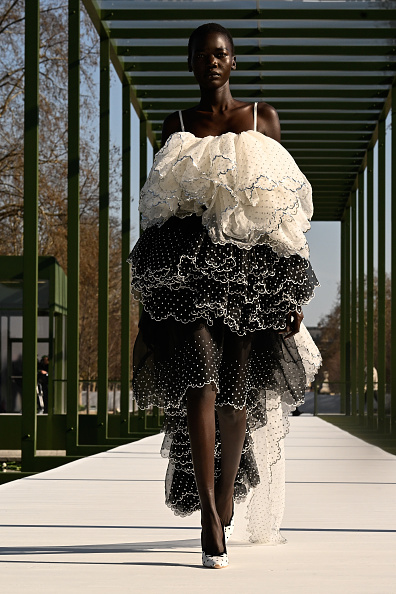 Model Achol Ayor appeared on the runway for the Christian Dior Women’s Fall/Winter 2026–2027 ready-to-wear collection, wearing a two-tone white spaghetti-strap gown featuring a voluminous ruffled bodice and a black layered high-low skirt embellished with white polka dots.