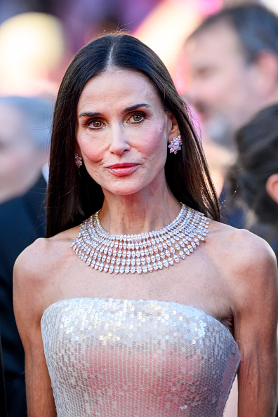 Demi Moore wore custom Jacquemus satin pumps with kitten heels, an elegant Jacquemus clutch, and a white-gold Chopard necklace featuring heart-shaped diamond accents.