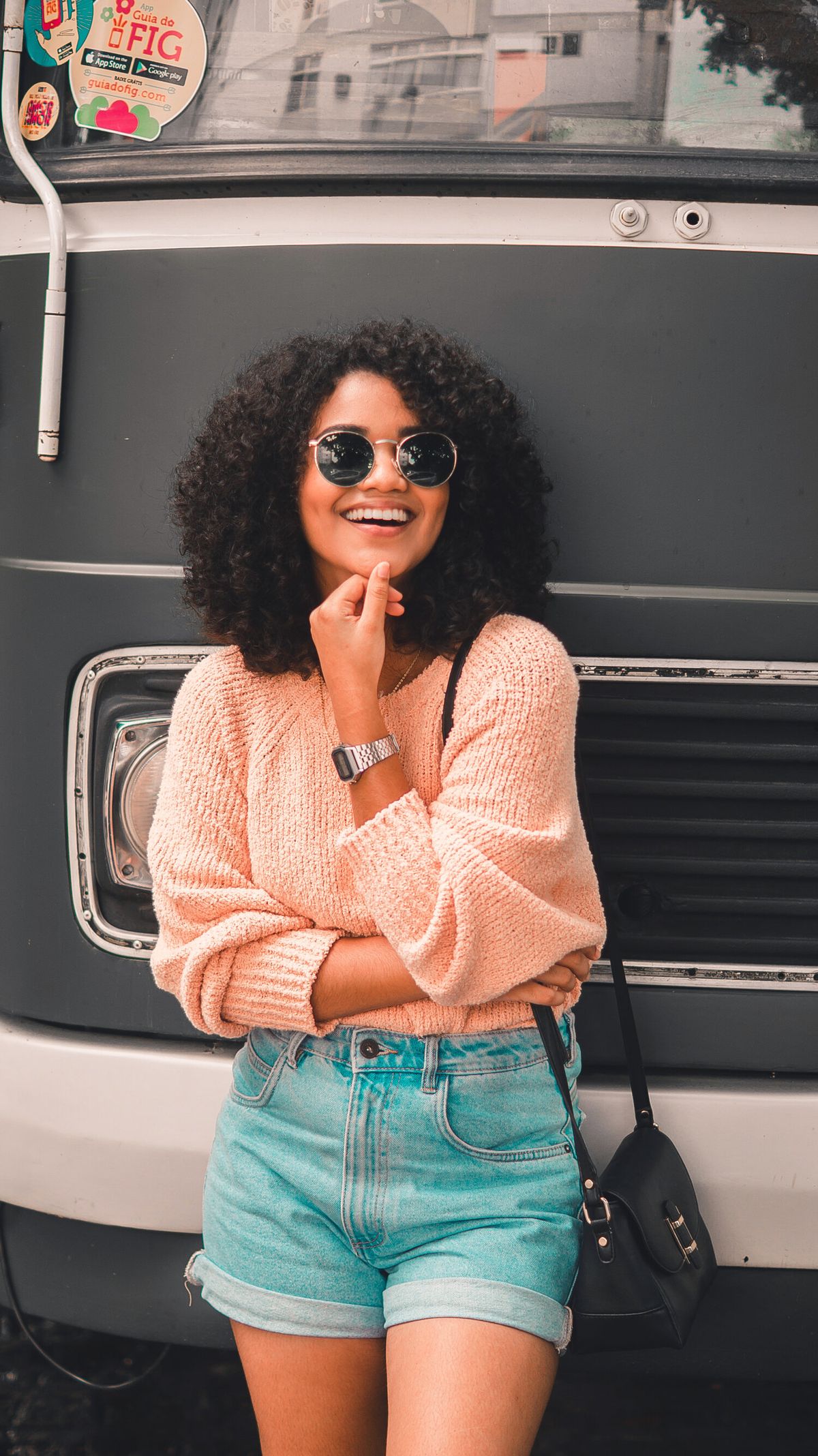 a woman is wearing a peach sweater and denim shorts