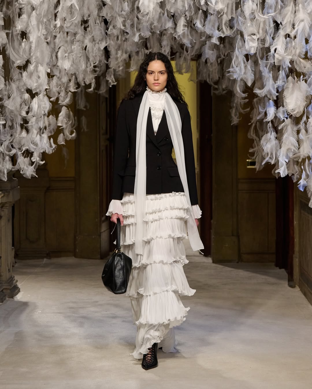 A fashion model walked the Elisabetta Franchi Womenswear Fall/Winter 2026/2027 collection presentation dressed in a black and white ensemble similar to Jennifer Lopez’s look from the “Office Romance” NYC premiere tour.