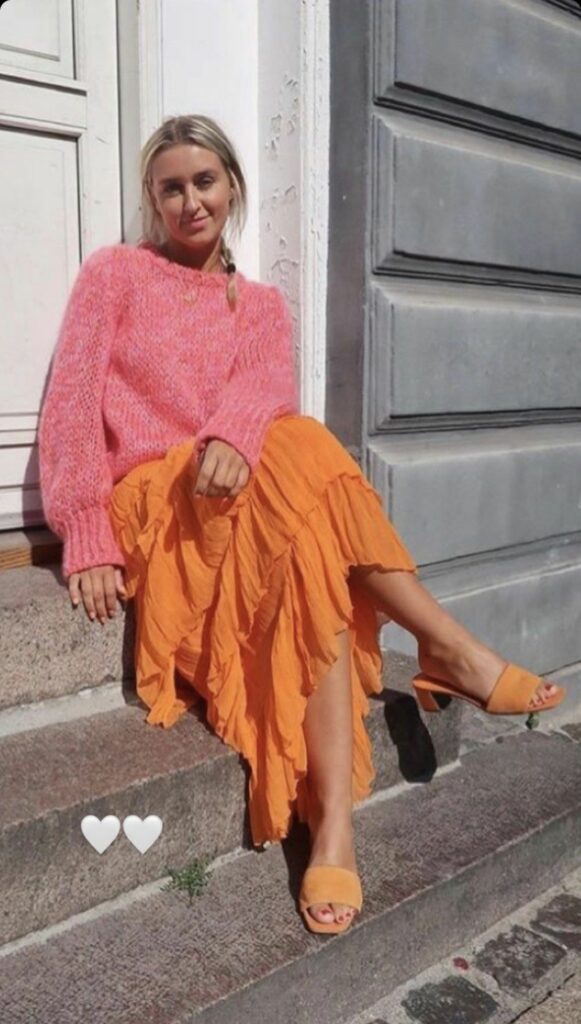 a model wearing peach sweater and orange skirt